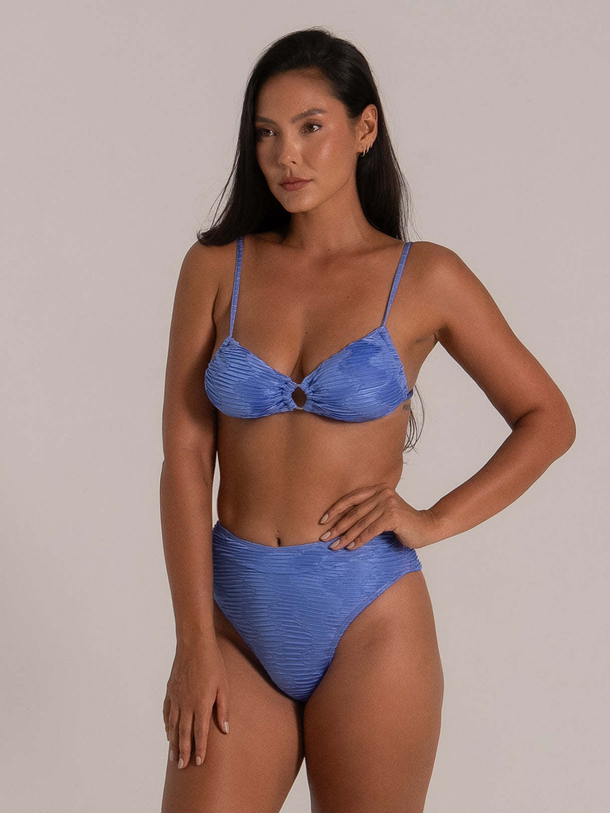 Three-quarter view of textured blue bikini top with ring center and soft shimmer finish