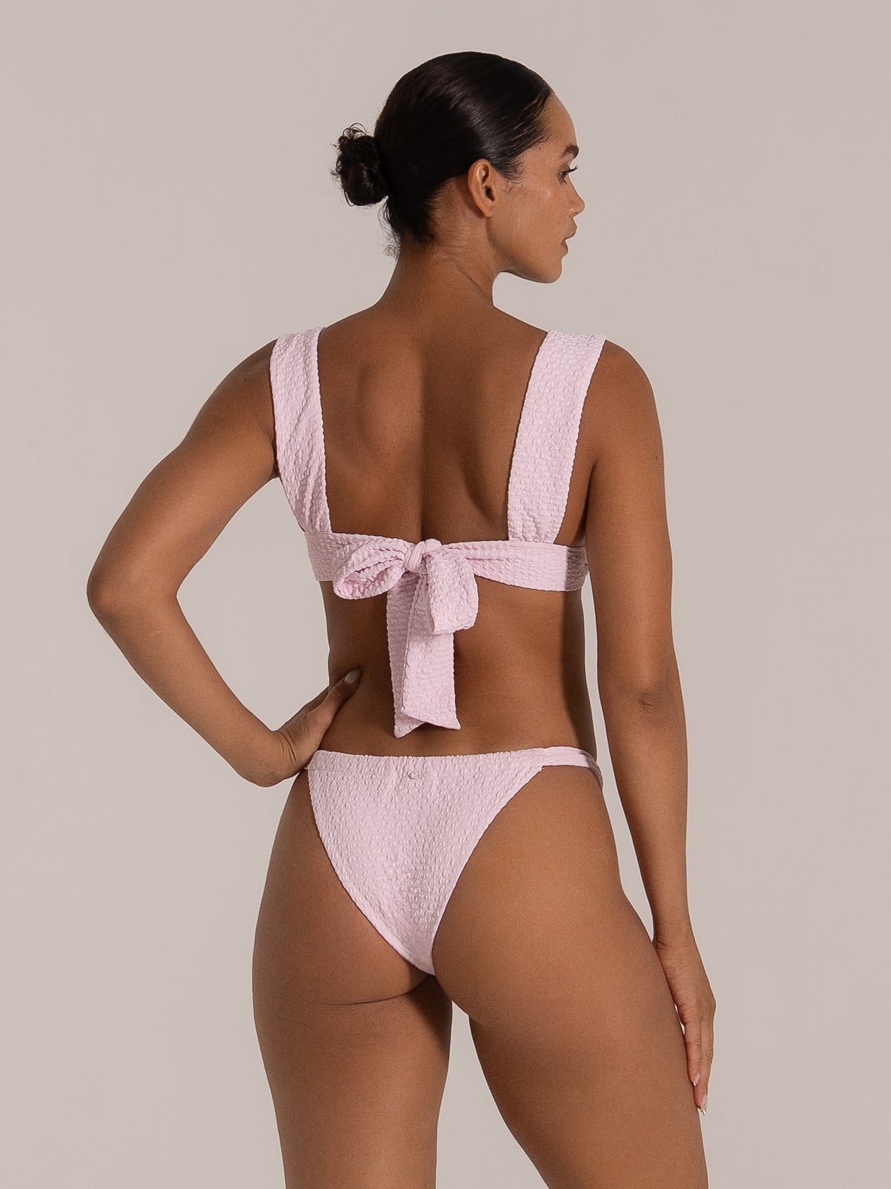 Side view of soft pink bikini top featuring wide shoulder straps and knotted back tie