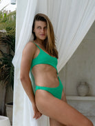 Stylish green jacquard one-piece swimsuit with hollow-out accents and customizable straps worn by a woman.