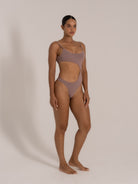 Angled front view of taupe cutout one-piece swimsuit with high-cut legs and scoop neck