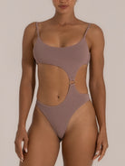 Front view of a woman wearing a taupe one-piece swimsuit featuring side cutouts and a gold ring detail at the waist, combining sleek minimalism with a modern silhouette.