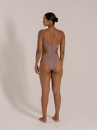Back view of taupe textured one-piece swimsuit with side cutouts and adjustable straps