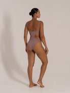 Side back view of taupe high-leg cutout one-piece swimsuit with scoop back
