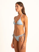 Side view of woman wearing baby blue textured tie side bikini bottom with cheeky cut.