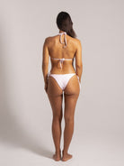 Back view of a woman in a light pink textured triangle bikini set with minimal coverage
