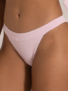 Side angle of light pink textured bikini bottom showing curved waist and stretch fabric
