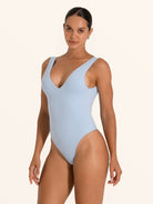 Woman in baby blue textured V neck one piece swimsuit with flattering high leg design.