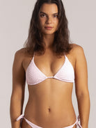 Model wears a textured light pink triangle bikini top, front close-up showcasing soft padded cups and halter tie straps.
