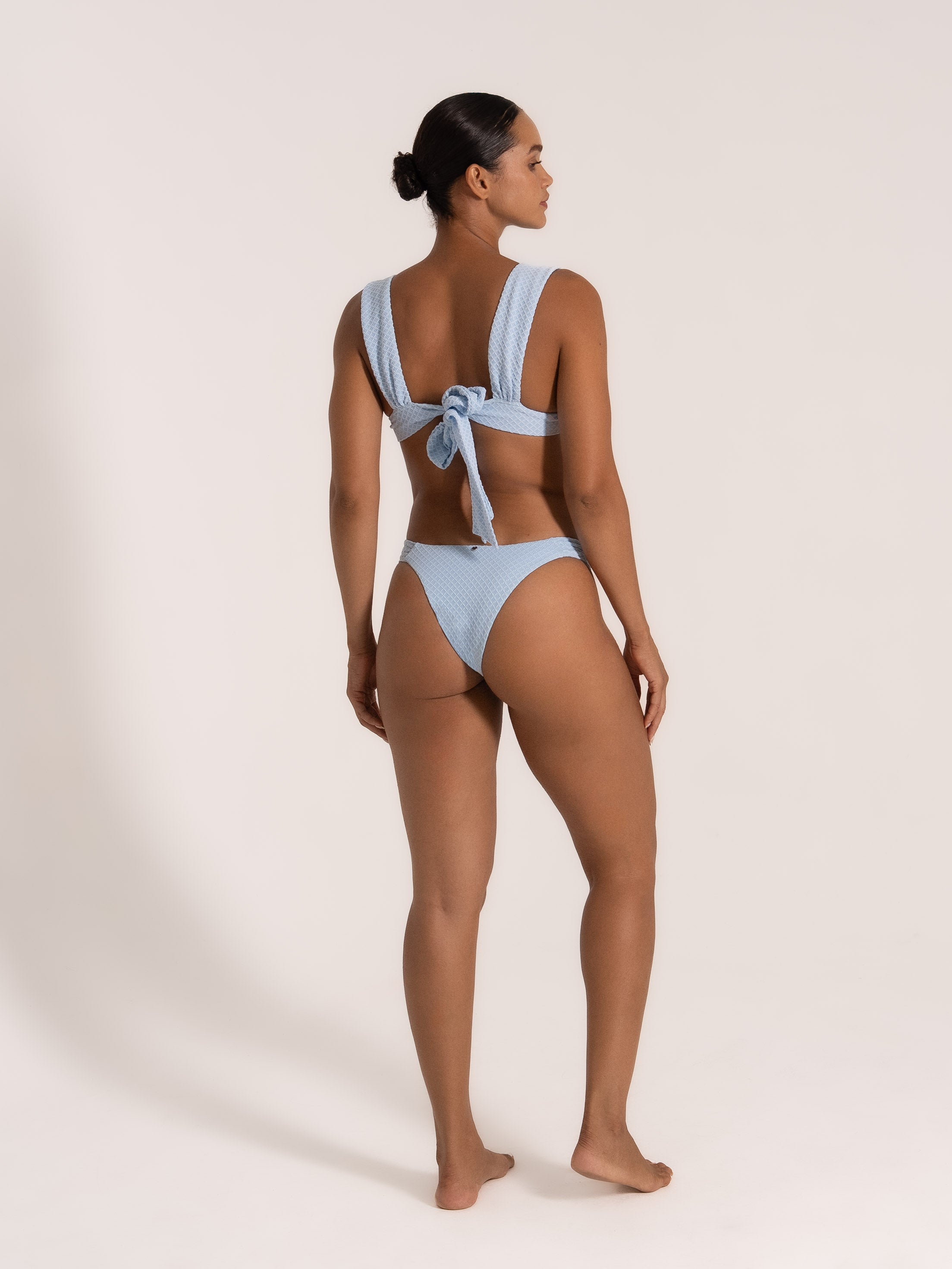 Back view of textured baby blue bikini with thick shoulder straps and large bow tie
