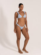 Model wearing baby blue textured triangle bikini set with tie-side bottom