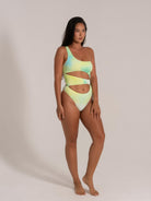 Side angle of woman in trendy green-yellow gradient swimsuit featuring one shoulder and artistic side cutouts