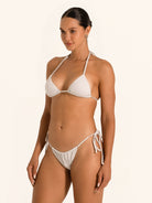 Model posing in shimmer silver triangle bikini top with adjustable halter straps.