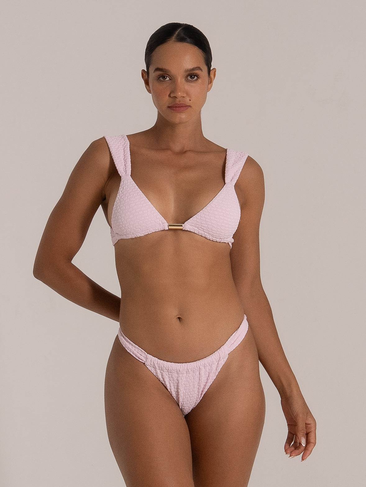 Front-facing view of light pink textured triangle bikini top with gold metal accent