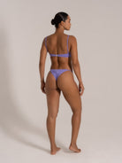 Angled back view of purple twist front bandeau bikini set on model