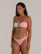 Model wearing pastel colorblock bandeau bikini top with central ring accent