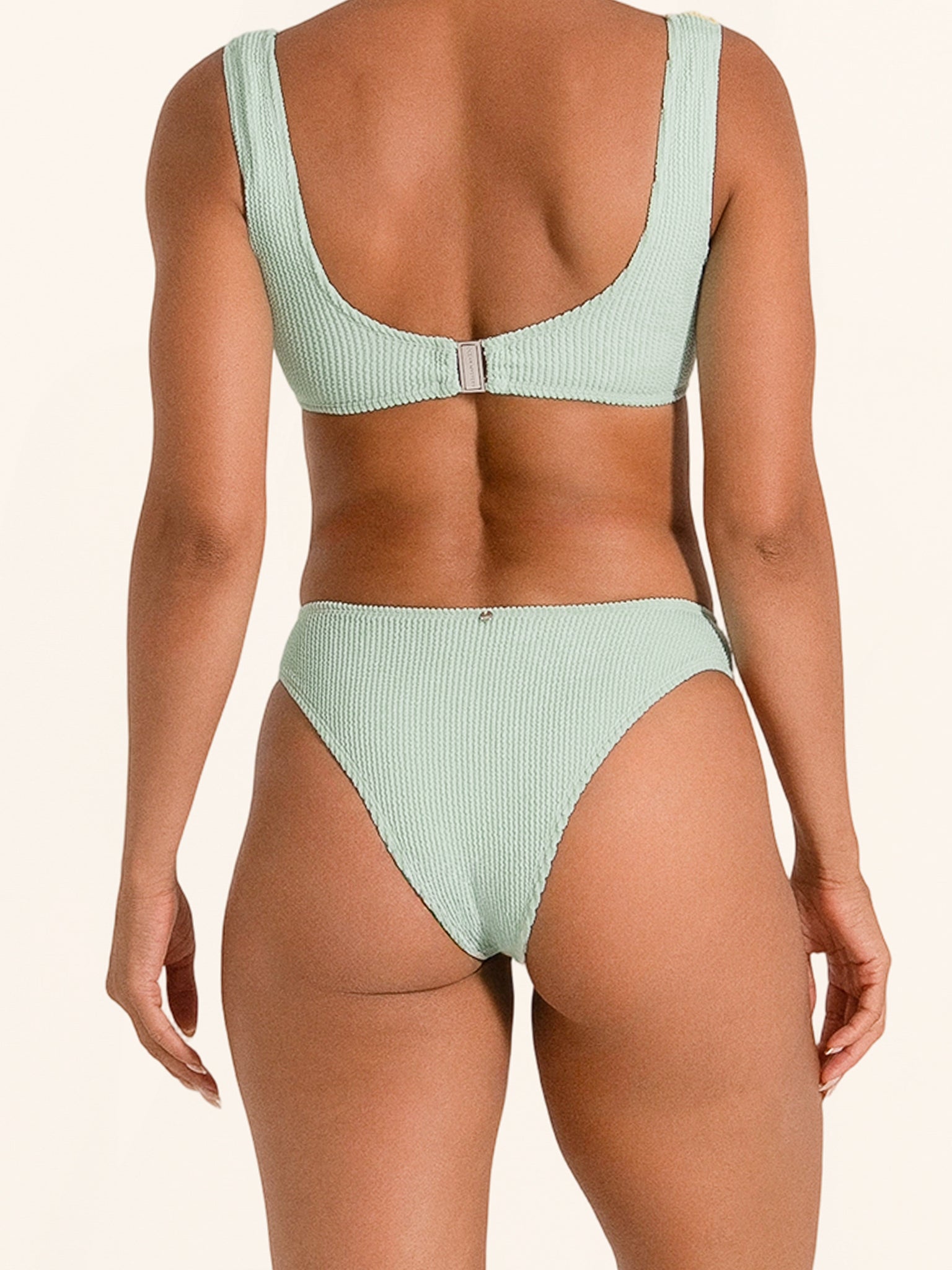 Two-tone bikini bottom in mustard and mint with textured fabric.