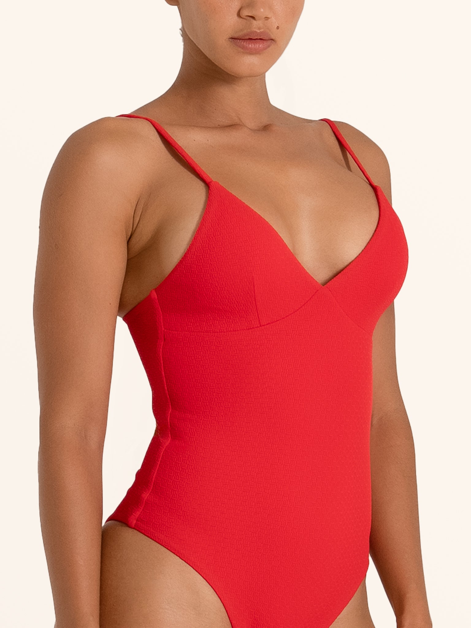 Side angle of red one piece swimsuit with flattering V neck and high cut leg design.