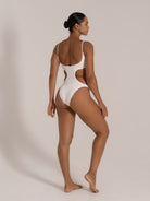Angled back view of a textured white one-piece swimsuit featuring side cut-outs