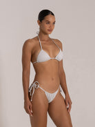 Model wearing a sparkling white bikini with triangle top and ruched bottoms