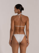 Back view of woman wearing white glitter triangle bikini set with halter tie top and string tie sides