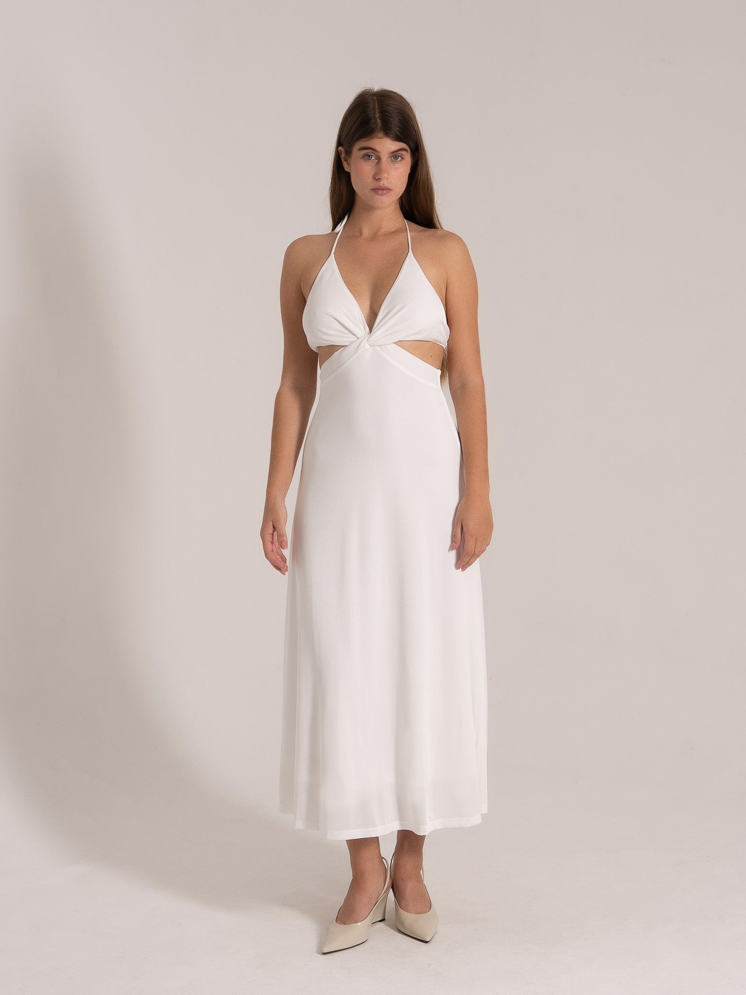 Woman in white halter maxi dress with cut-out waist, front view