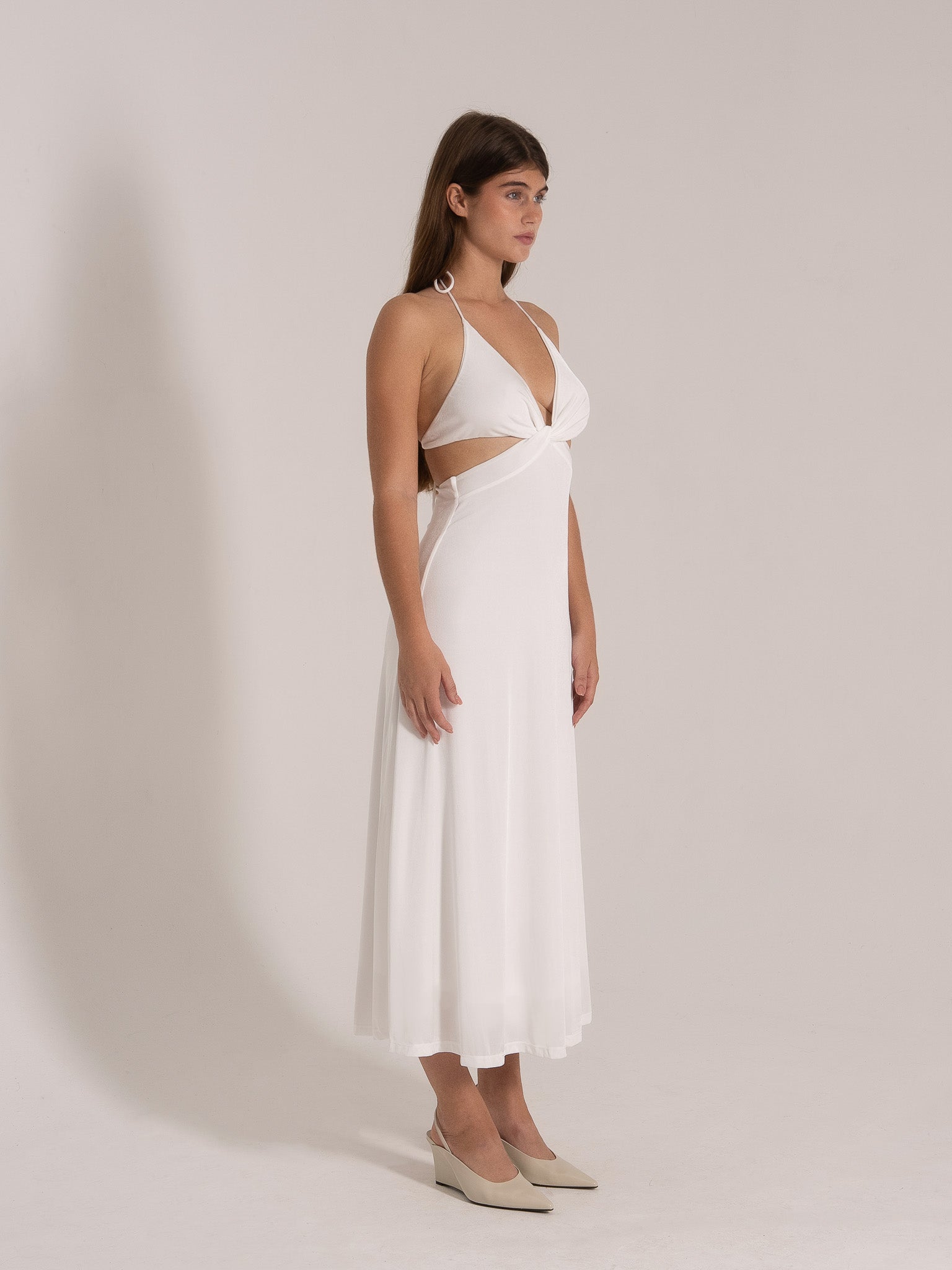 Side profile of white twist-front halter maxi dress with flowy hem