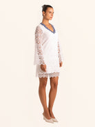 Full body view of white lace dress with long sleeves and scalloped hem