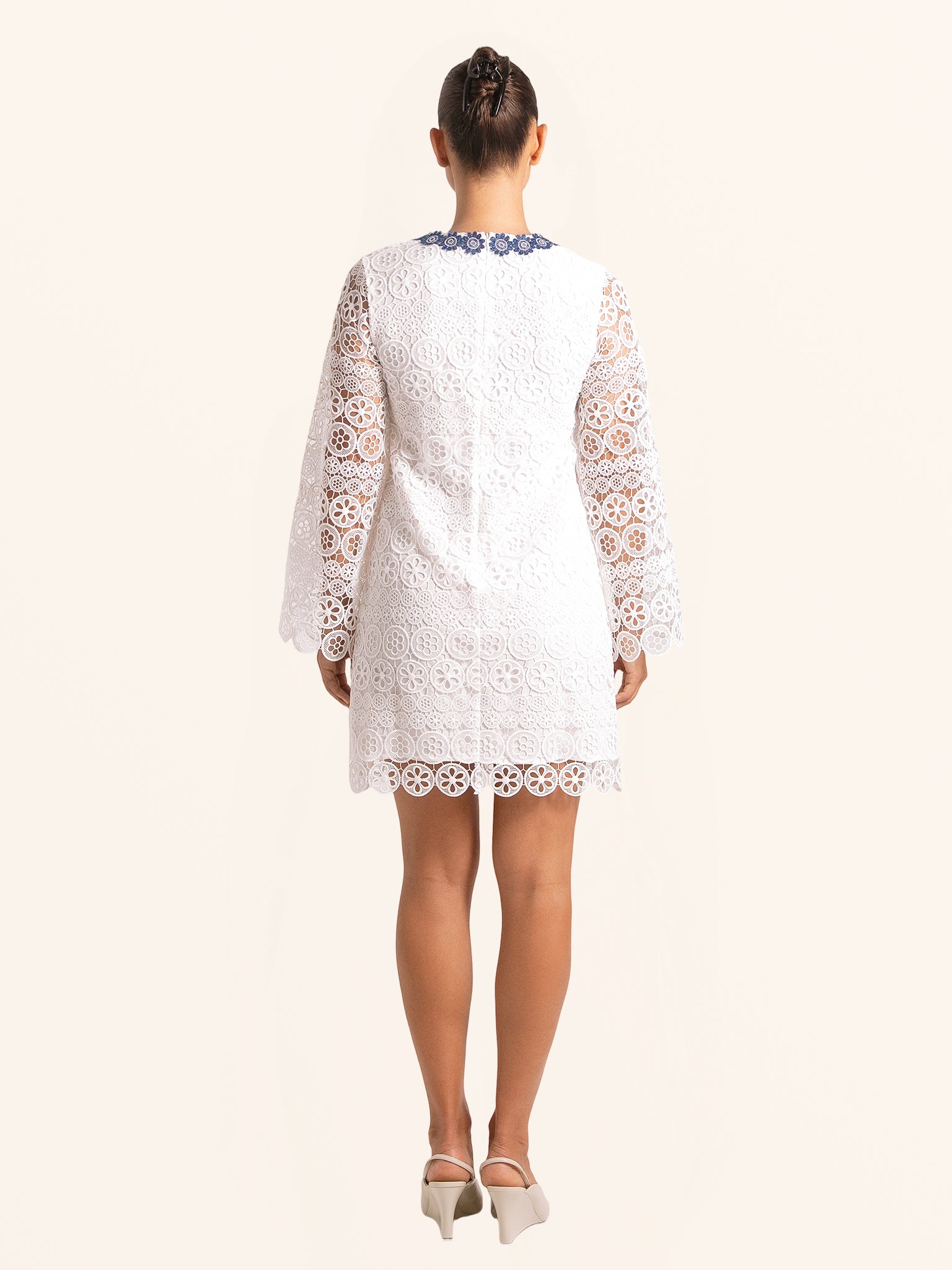 Back view of white lace mini dress with floral lace design and blue neckline trim