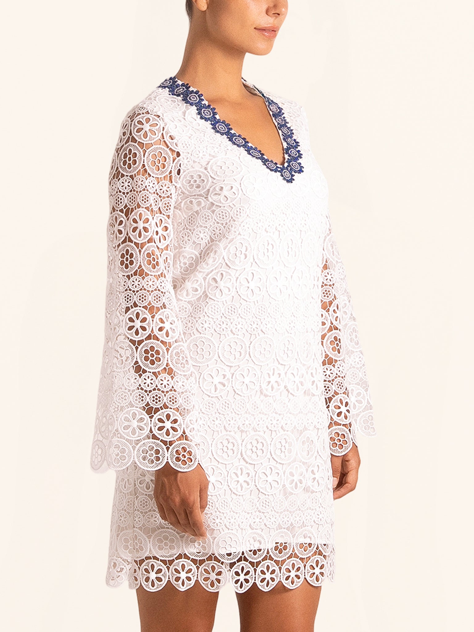 Closeup side angle of white lace mini dress featuring floral lace pattern