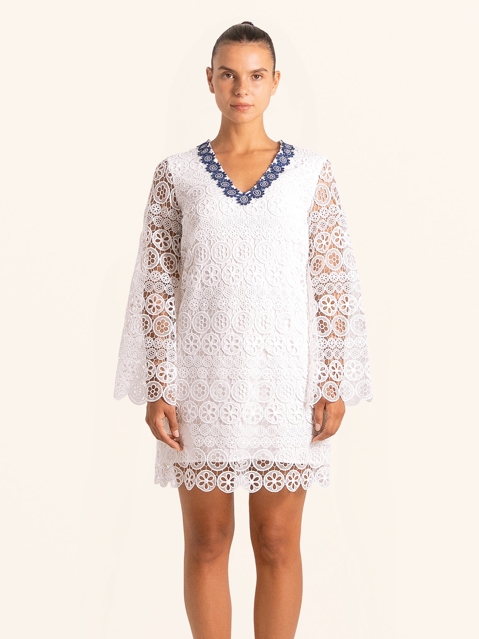 Front view of white lace mini dress with long bell sleeves and V neckline