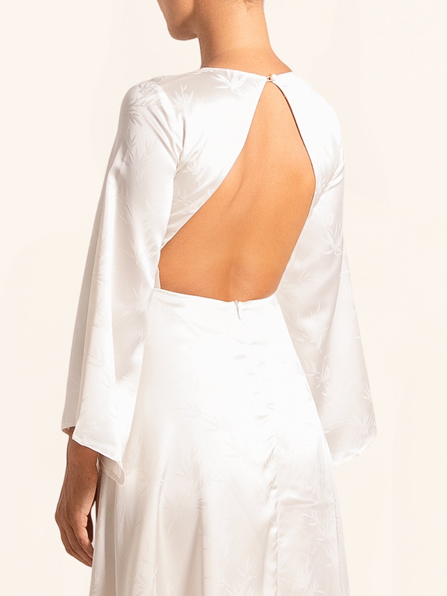 Back view of white long sleeve dress with open back cut out detail