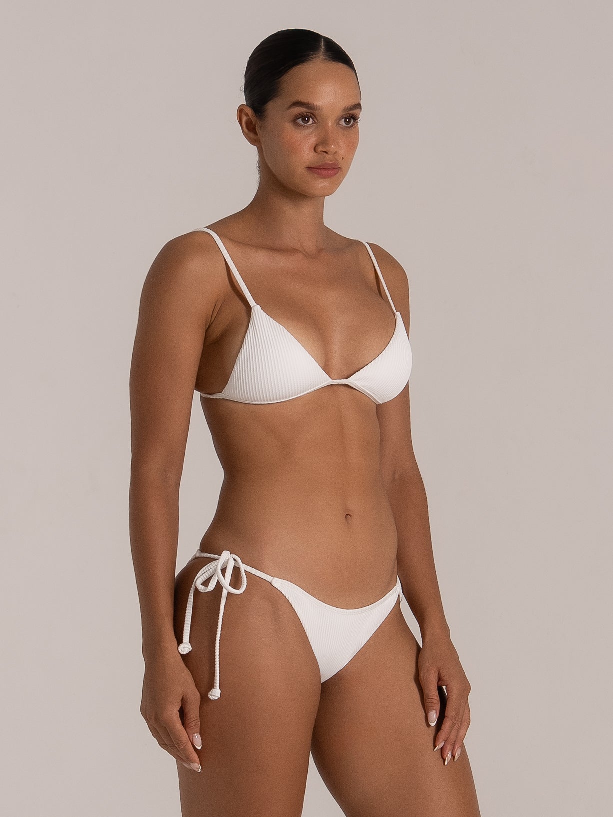 Side angle of white ribbed triangle bikini top with soft textured fabric and tie sides