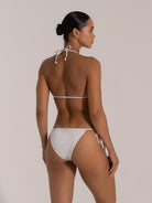 Woman wearing a white shimmer triangle bikini with tie-back, back view.