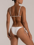 Angled view of white tie-side bikini bottom with ribbed texture.
