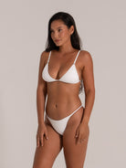 Stylish white textured bikini with triangle top and minimal coverage bottoms from side front angle