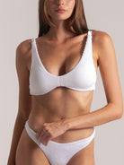 Close-up of woman in white textured bikini set featuring a V-neck top and matching high-leg bottoms