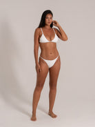 Front view of model in white triangle bikini set, featuring minimalist design and textured fabric.