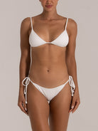 Woman wearing a white ribbed triangle bikini with side-tie bottoms, front view