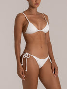 Side view of a woman in a white ribbed triangle bikini set with adjustable straps and string-tie bottom