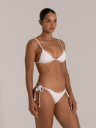 Model in white triangle bikini with ribbed texture and rope tie sides, angled pose