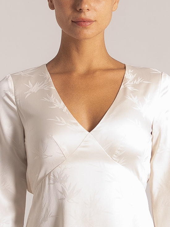 Close-up front view of white lace sundress with navy embroidered V-neckline