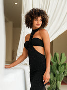 Woman in a black stand-collar sequin dress with a figure-flattering cut, a daring slit, and double-layer fabric.