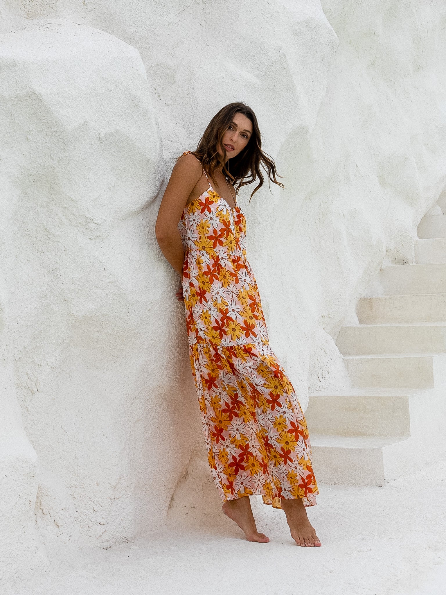 Floral long dress on a woman standing by the water in a serene setting.