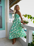 Woman wearing a spaghetti strap green floral dress on a beachfront villa terrace