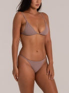  A woman wearing a pastel-colored triangle bikini set, showcasing a sleek and fit physique in a stylish swimwear pose.