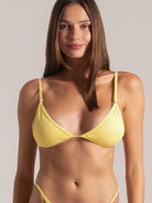Front close-up of model smiling in a yellow triangle bikini top with fine texture