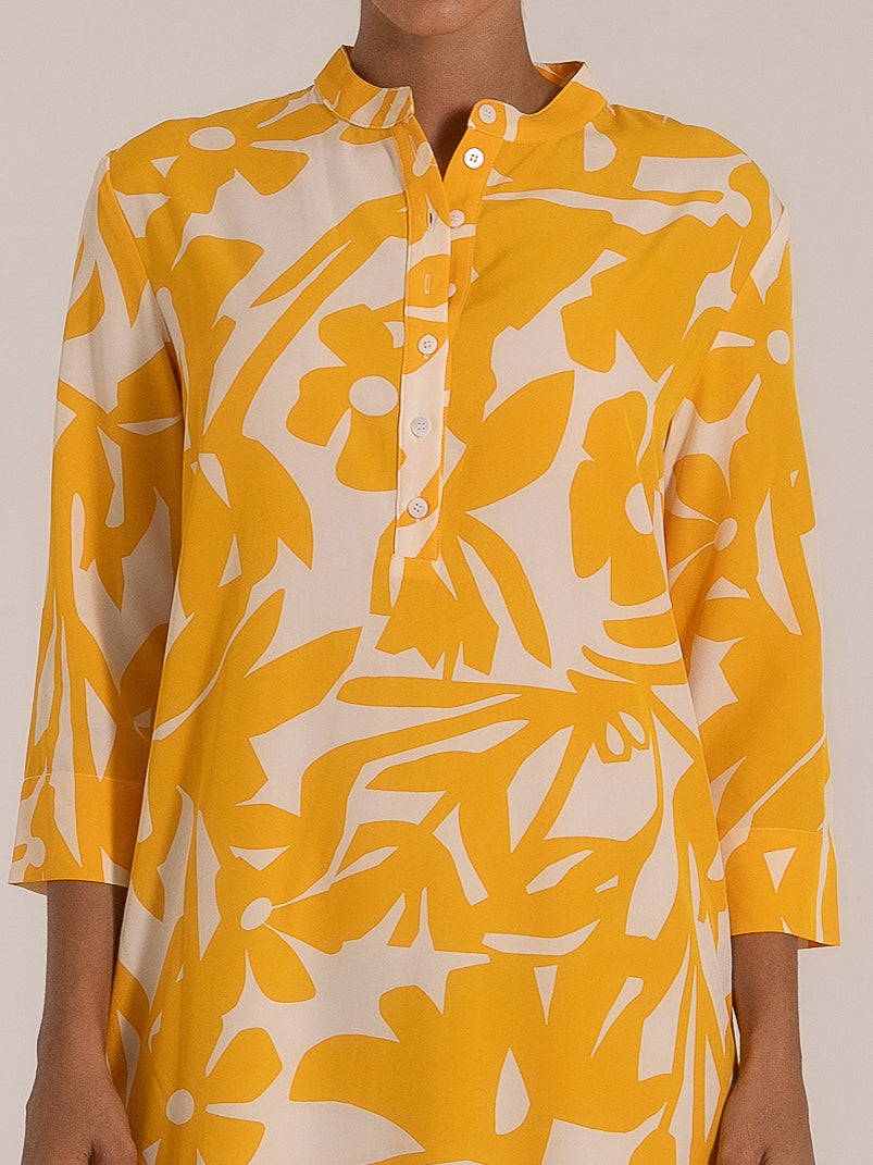 Close-up of a yellow floral print shirt dress with button front and mandarin collar.