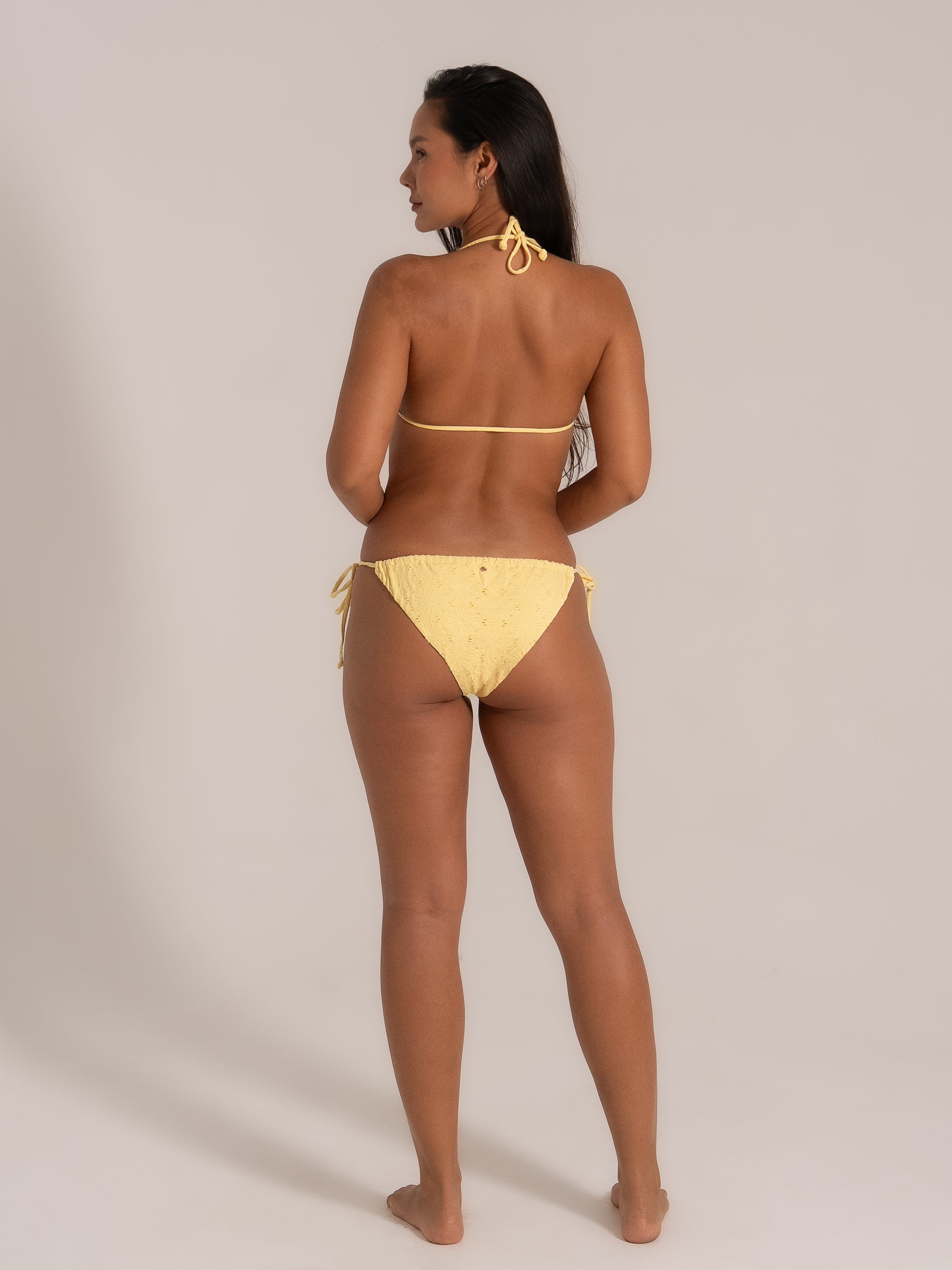 Model wearing yellow bikini with ring detail, back view