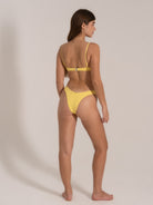 Model wearing a yellow textured bikini set with thin adjustable straps, back view.