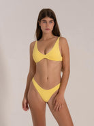 Front view of woman wearing yellow textured bikini top with scoop neckline